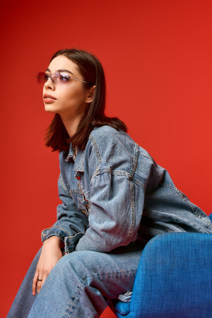 A stylish young woman poses confidently in her denim outfit against a bright backdrop.の写真素材