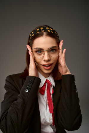Pretty student wearing a uniform shows off her stylish look while posing in a studio setting.