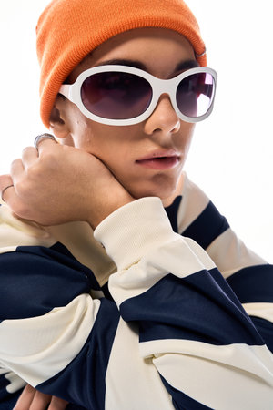 A confident teenager in a striped polo and orange hat showcases modern style.の写真素材