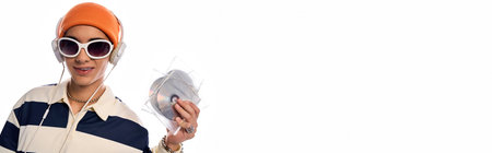 A fashionable teenager in a striped long sleeve polo and orange hat holds a shiny CD while smiling, bannerの写真素材