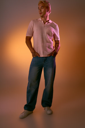 Handsome young man stands confidently in relaxed fashion against a soft gradient background.の写真素材