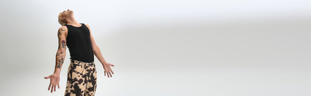 Young man poses in trendy attire, showcasing a chic lifestyle against a light background.の写真素材