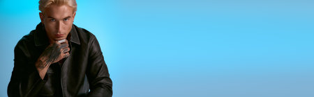 A confident young man showcases his fashion style against a striking blue backdrop.の写真素材