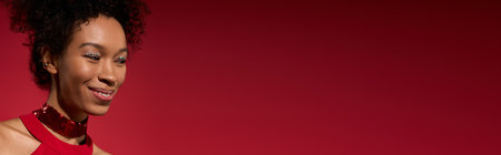 A beautiful young woman smiles brightly, showcasing her charm in a striking red environment.の写真素材