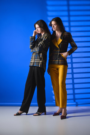 Twin sisters exude beauty and style in trendy outfits within a chic modern setting.
