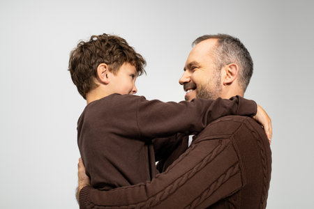A cheerful father lifts his smiling son, creating a heartwarming moment of joy and connection.の写真素材