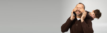 A father enjoys a joyful moment with his son hiding behind him during family time.の写真素材