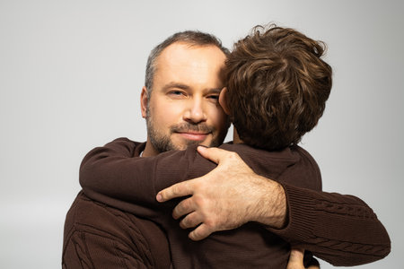 A father shares a loving hug with his young son, showcasing their bond and affection.の写真素材