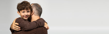 A joyful father holds his little son in a tender hug, showcasing their close bond and affection.の写真素材