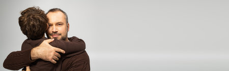 A father holds his young son tightly, showcasing their strong emotional connection and love.の写真素材