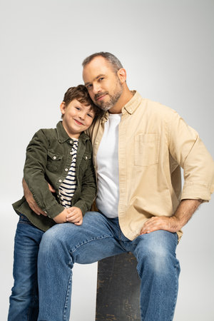 A father and his young son share a warm embrace, radiating love and happiness in their cozy space.の写真素材