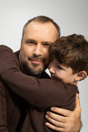 A father and his little son share a tender hug, radiating love and joy in a warm atmosphere.の写真素材