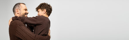 A man warmly holds his little son in a loving embrace, sharing laughter and joy indoors.の写真素材