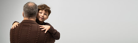 A father holds his young son close, both dressed in cozy sweaters, radiating love and togetherness.の写真素材