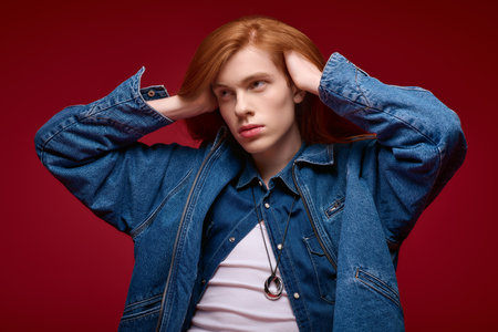 A confident young person with bright red hair showcases their pride in a creative space.