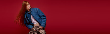 A person confidently shows their unique style against a bold red backdrop, embracing their identity.の写真素材