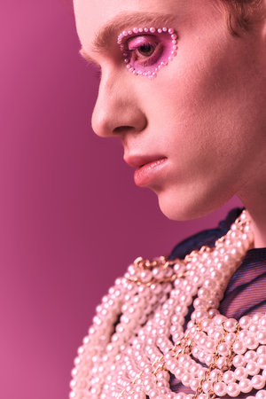 A person displays pride with vibrant makeup and trendy clothing in an artsy setting.の写真素材