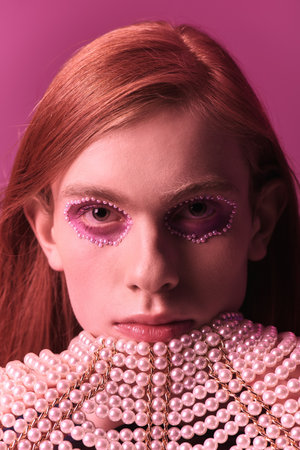 Person embodies pride and creativity with unique makeup, styled hair, and an artistic collar.の写真素材