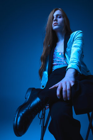 A person exudes energy and pride while seated in a striking blue backdrop, showcasing individuality.の写真素材