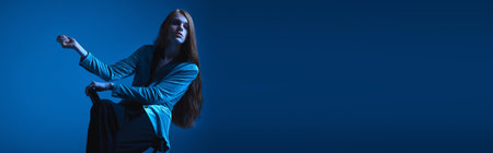 A person confidently embraces their pride, radiating joy against a bold blue background.の写真素材