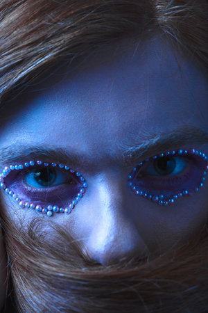 A person showcases unique makeup with colorful beads around their eyes, celebrating pride.の写真素材