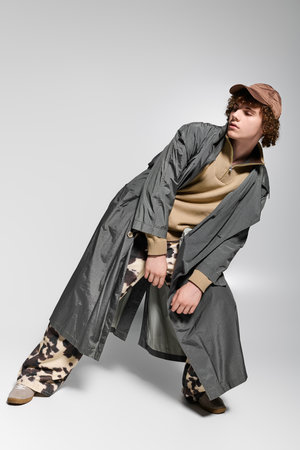 Teen poses confidently in a trendy long coat and patterned pants, showcasing their style.の写真素材