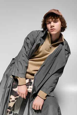 Trendy teenager strikes a bold pose in stylish outfit against a simple backdrop.