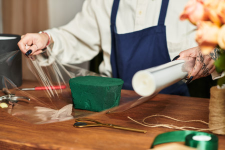 Young florist skillfully wraps floral foam while arranging fresh flowers in a cozy shop, banner