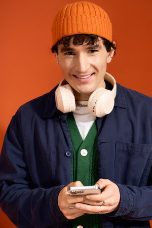 Handsome man in a colorful outfit joyfully interacts with his smartphone, exuding confidence.