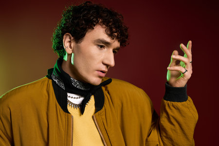 A handsome man showcases his fashion sense with flair, highlighted against a colorful backdrop.