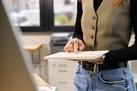 A young woman focuses on her keyboard in a bright office space.の写真素材