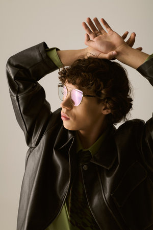 Handsome young man with curly hair showcases fashion sense while posing artistically indoors.
