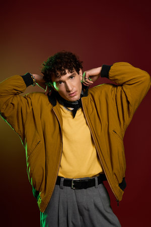 Stylish man poses confidently in vibrant attire against a bold backdrop, exuding charm and style.