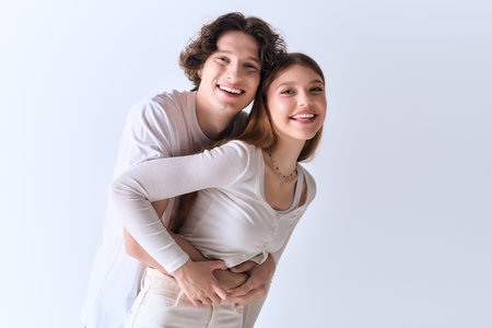 A happy young couple poses together, radiating love and warmth in a stylish grey studio.の写真素材
