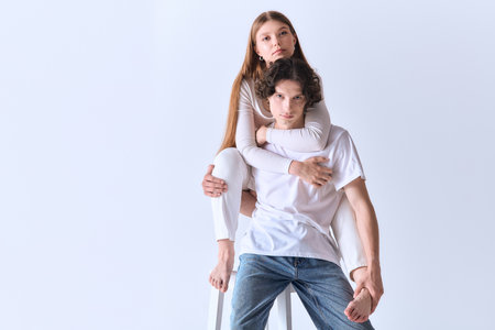 Young couple embraces in a soft grey studio, radiating love and happiness together.