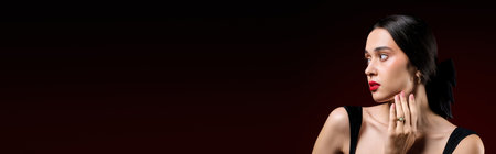 Stylish woman highlights her beauty with striking makeup against a captivating red background.