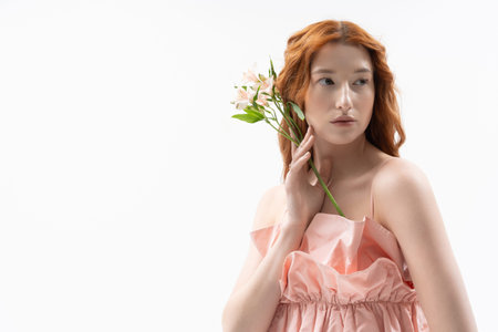 Young woman poses effortlessly with flowers, embodying spring beauty and stylish fashion.の写真素材