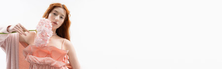 A young, beautiful redhead poses with pastel flowers, showcasing spring fashion in a serene studio, bannerの写真素材