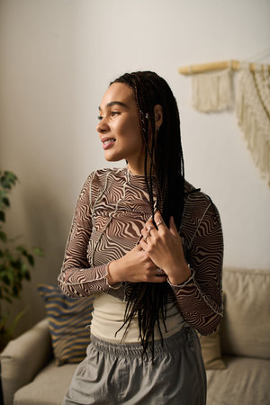A young African American woman with braids relaxes in her stylish apartment, embracing tranquility.