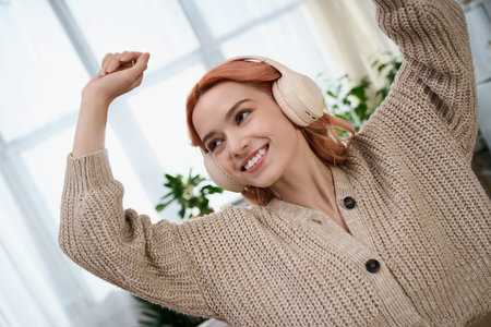 A young woman with vibrant hair joyfully dances indoors, enjoying the music.