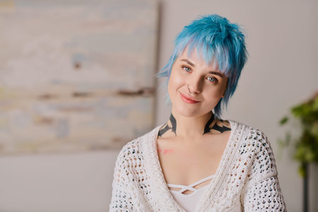 Stylish young woman with blue hair smiles warmly, embracing a vibrant indoor atmosphere.