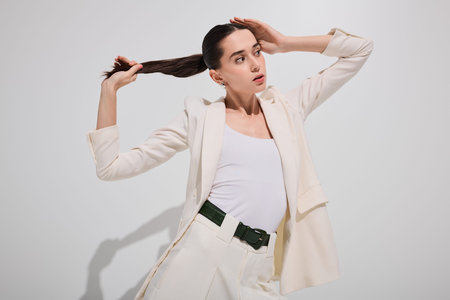 Stylish woman poses gracefully, highlighting her chic outfit and confident demeanor in soft light.