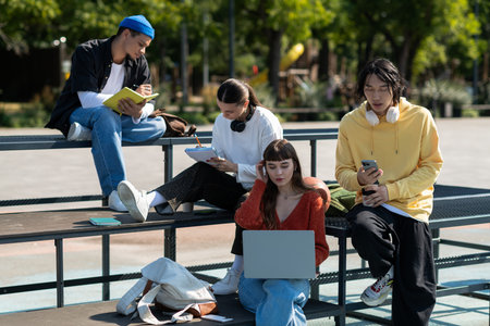 Four friends gather under the sun, laughing and collaborating on creative projects and plans.の写真素材