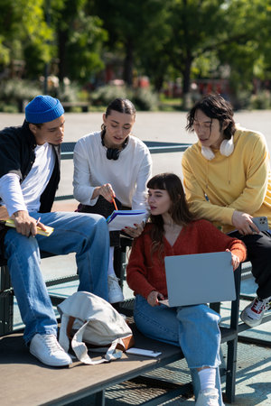 Four friends gather happily outside, exchanging thoughts and creativity in a sunny space.