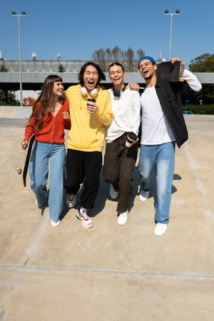 Four young friends laugh and embrace the warmth of a sunny day in the park.