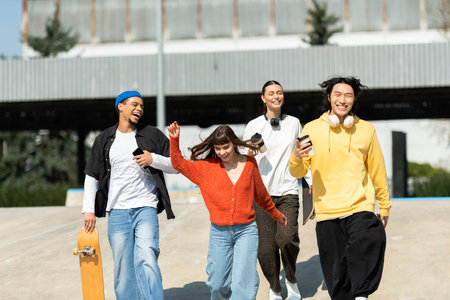 Group of friends share laughter and fun while walking through a skate park under a clear sky.の写真素材