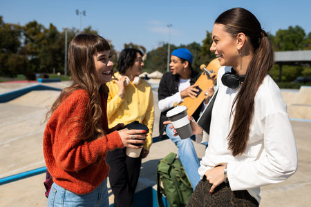 Young friends share joyful moments with drinks while soaking up the sun in the park.