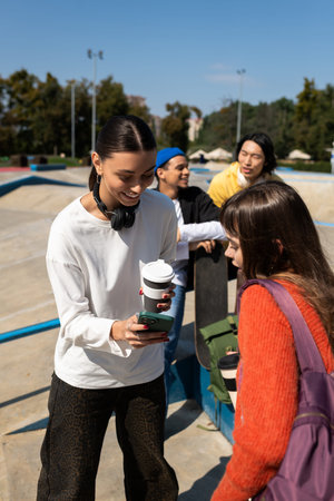Friends enjoy a sunny day at a skate park, bonding over shared stories and drinks.