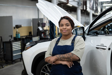 A young female mechanic works on a car in a vibrant auto repair shop.の写真素材