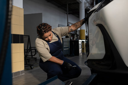 Skilled female mechanic in overalls performing maintenance on a car, showcasing expertise.
